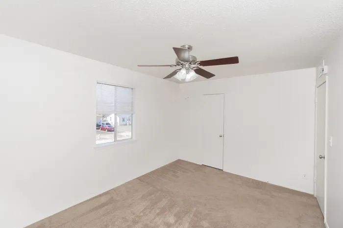 Bedroom with carpet flooring, ceiling fan with light, window with blinds, and standard closet and entry door