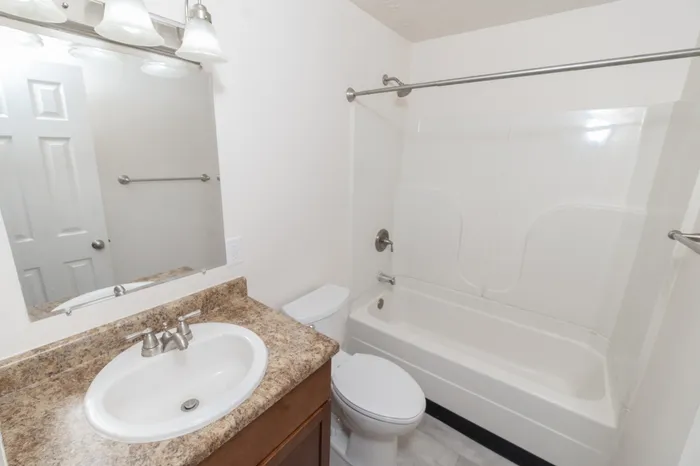 Bathroom with tub and shower combo, vanity with sink, mirror with lighting, and modern fixtures