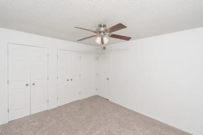 Bedroom with carpet flooring, ceiling fan with light, window with blinds, and closet and entry doors