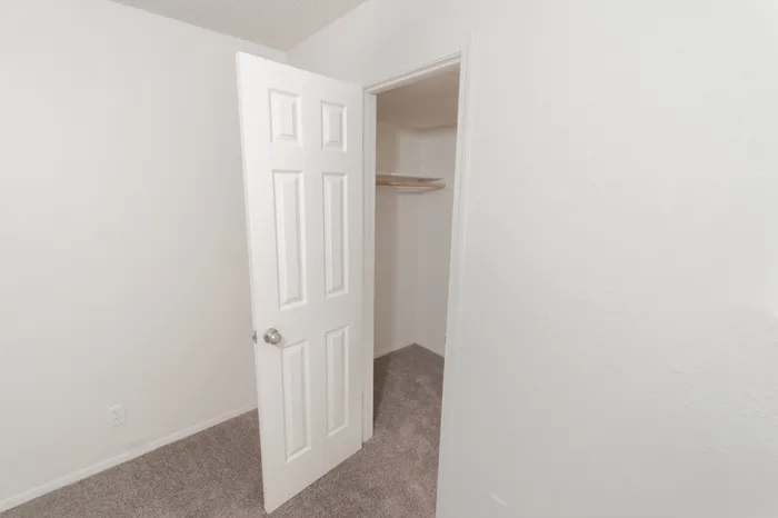 Walk in closet with carpet flooring, hanging rod, shelf storage, and white door entry
