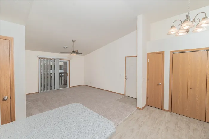 Spacious living room in Plainview Park apartment with vaulted ceiling, carpet flooring, ceiling fan, natural light, and access to private balcony