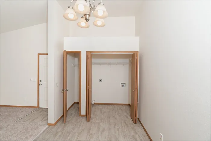 In unit laundry closet in Plainview Park apartment with washer dryer hookups, shelving, and vinyl flooring near entryway