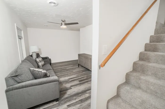 Living room with wood style flooring, ceiling fan, natural light, and staircase entry in Dryden Place Townhomes