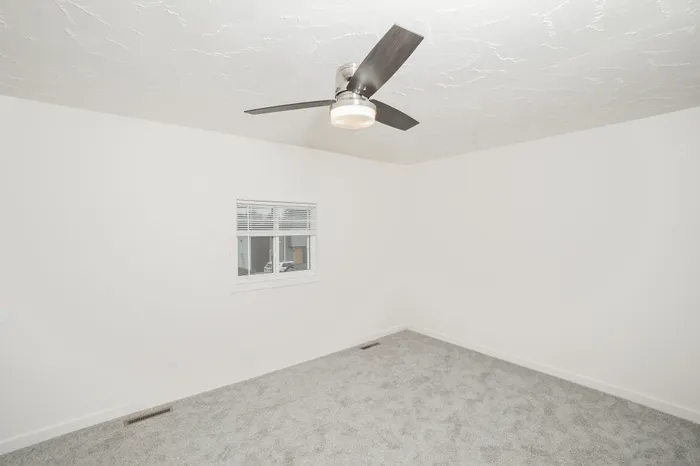 Bedroom with carpet flooring, ceiling fan, neutral walls, and window in Dryden Place Townhomes