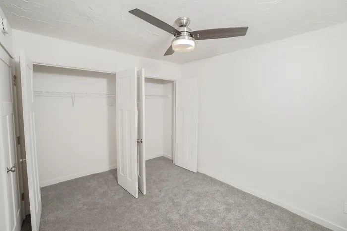 Bedroom with carpet flooring, ceiling fan, neutral walls, and window for natural light in Dryden Place Townhomes