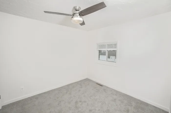 Bedroom with carpet flooring, ceiling fan, and double closets with sliding doors in Dryden Place Townhomes