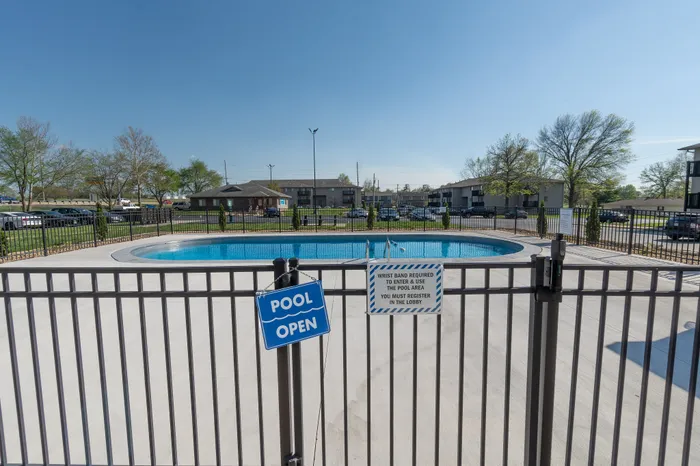 Inviting outdoor swimming pool with clear blue waters, surrounded by a secure fence and lush greenery, promising relaxation and leisure.