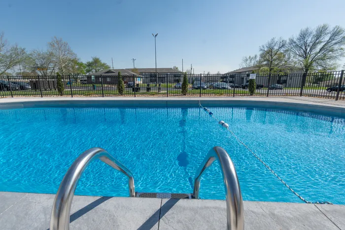 Inviting outdoor swimming pool with clear blue water, surrounded by a secure fence and lush greenery, perfect for relaxation and enjoyment.