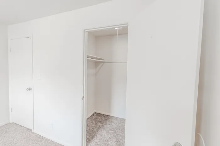 Open walk-in closet inside the bedroom of the Classic 1 Bedroom unit at Rosewood Village, offering ample shelving and storage space.