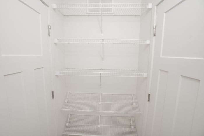 Bedroom closet at El Chaparral Apartments with open double doors and multiple white wire storage shelves.