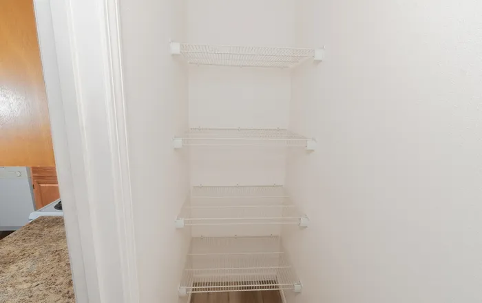 Walk in kitchen pantry at Quail Ridge East Apartments with multiple wire storage shelves and easy access from the main kitchen area.