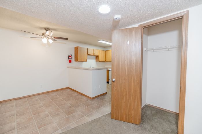 Charming apartment interior showcasing an open kitchen with wooden cabinetry, elegant tile flooring, and a cozy living space with a ceiling fan.