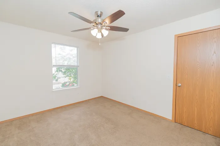 Bright and airy bedroom featuring a ceiling fan and a large window, perfect for creating a cozy retreat.