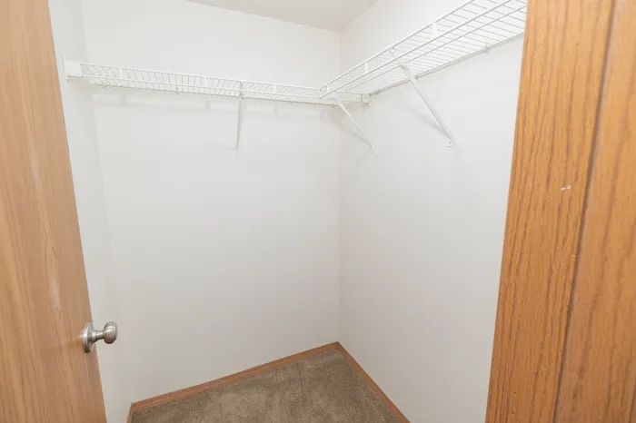 Spacious walk-in closet with white wire shelving and wooden detailing.