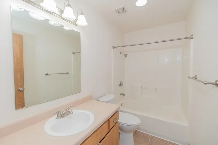Bright and spacious bathroom featuring elegant fixtures, large mirror, and pristine finishes.