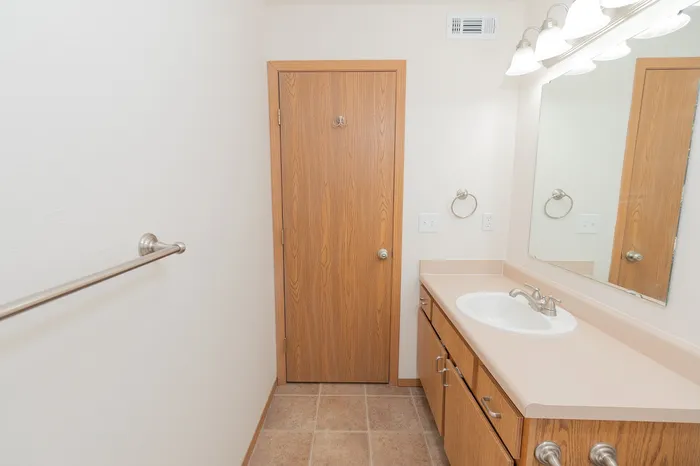 Bright and inviting bathroom featuring wood accents, a modern vanity, and ample lighting for a cozy atmosphere.