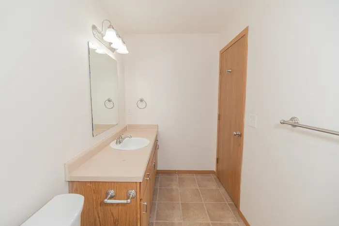 Bright and inviting bathroom featuring a sleek vanity with ample storage, elegant lighting, and modern fixtures.