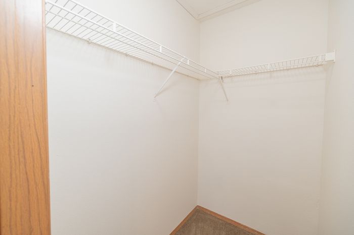 Spacious walk-in closet with white shelving, ideal for organized storage in a modern apartment.