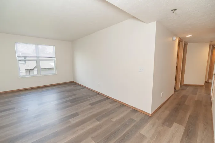Bright and airy room with elegant hardwood flooring and a large window offering plenty of natural light.