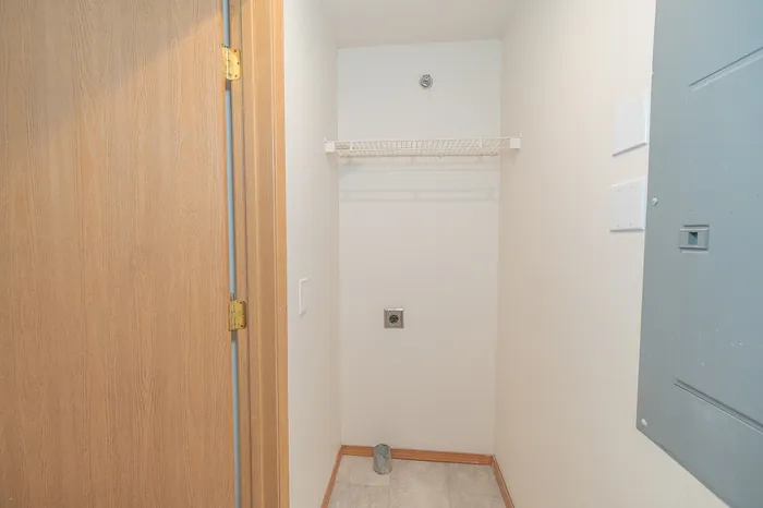 Bright laundry area with built-in shelf and utility connections, perfect for a compact washer and dryer setup.