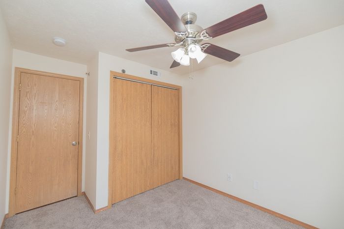Bright, cozy room featuring a modern ceiling fan and warm wood accents, ideal for a peaceful space.