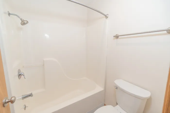 Bright and modern bathroom with a sleek white tub and shower combo, complemented by a convenient towel rack.