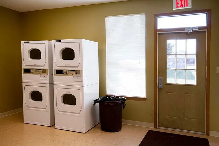 Modern apartment laundry room featuring double stackable washers and dryers, offering convenience and efficiency.