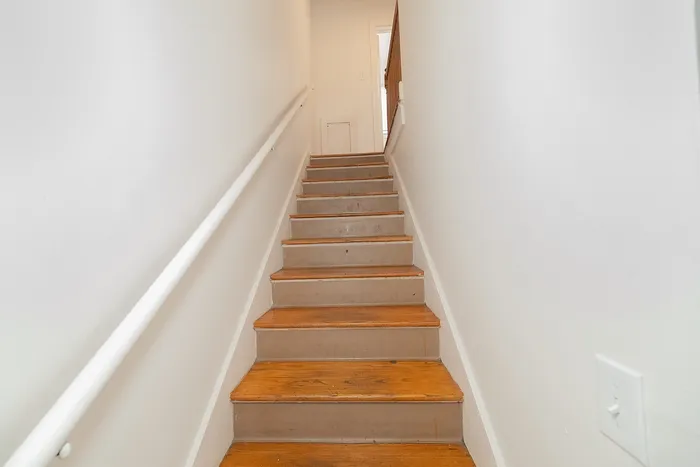 Charming wooden staircase with warm tones leading to a bright upper level in a cozy apartment.