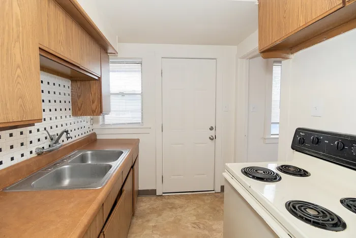 Charming kitchen with elegant wooden cabinets, modern electric stove, and attractive tiled backsplash.