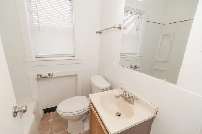 Bright, modern bathroom featuring elegant fixtures, full-sized mirror, and sleek tile flooring.