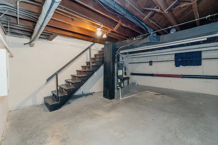 Spacious basement with exposed beams, perfect for storage or renovation possibilities.