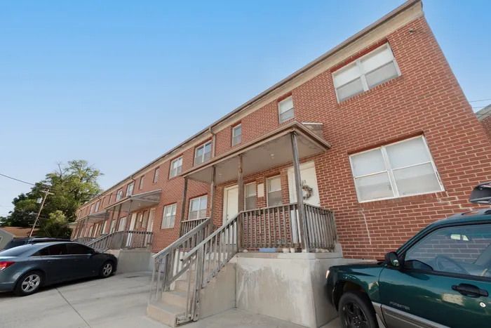 Charming brick townhouse with inviting front porch and ample parking, offering a perfect blend of urban convenience and suburban tranquility.