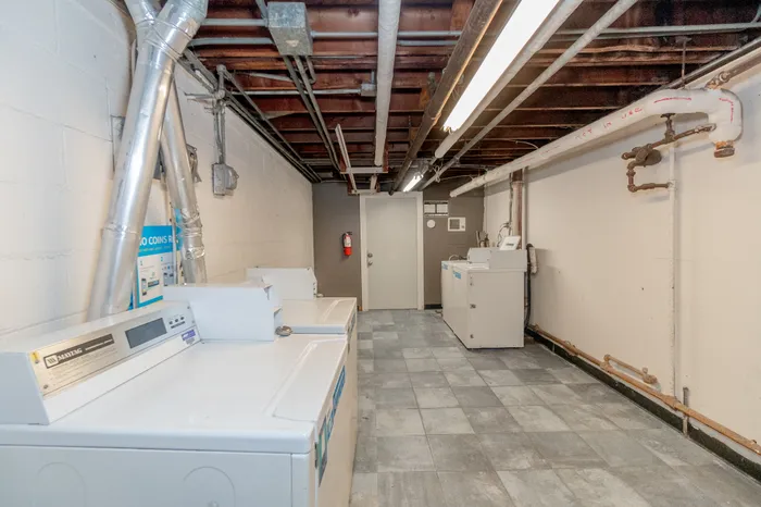 Spacious and practical laundry room with modern washing machines and industrial chic design, perfect for efficient apartment living.