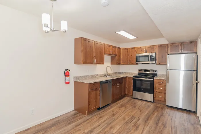 Open kitchen and dining area in a renovated Chesterfield Village apartment with stainless steel appliances, wood cabinetry, and modern lighting.