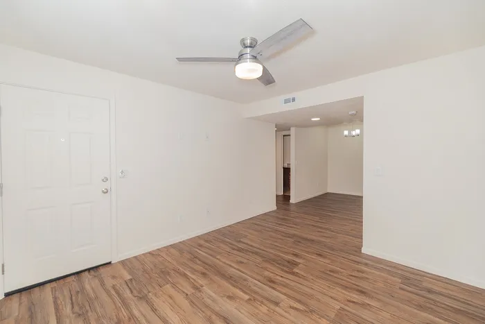 Spacious living room in a renovated Chesterfield Village apartment with wood look flooring, a ceiling fan, and an open layout.