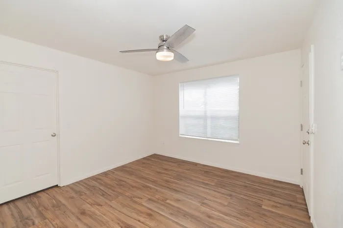 Bright renovated Chesterfield Village living room with wood look flooring, a ceiling fan, and a large window with blinds.