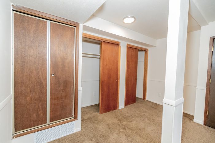 Spacious room with warm wood closets and plush carpeting, perfect for ample storage.