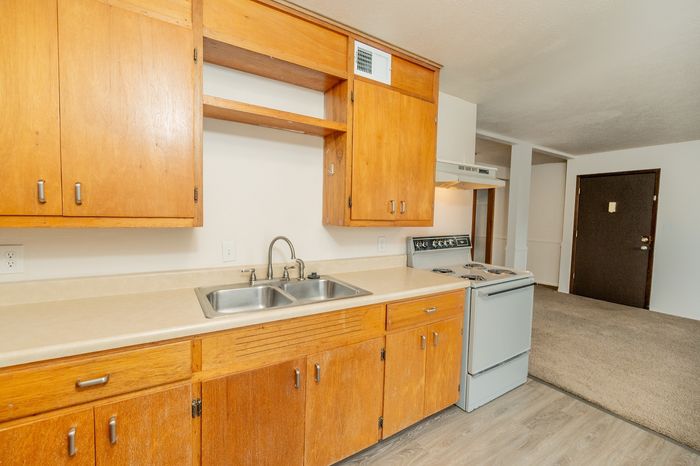 Charming kitchen with warm wooden cabinets, sleek countertops, and a classic oven, stepping into a cozy living area.