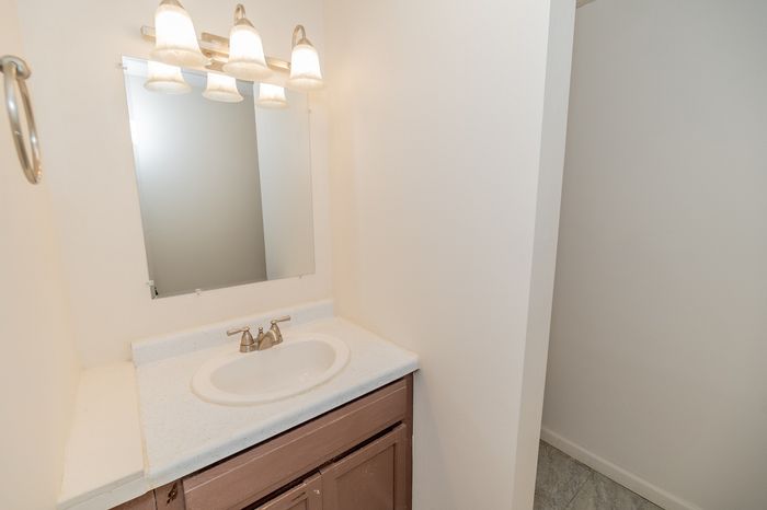 Bright and inviting bathroom with elegant lighting, a sleek mirror, and a classic sink setup, perfect for relaxation and convenience.