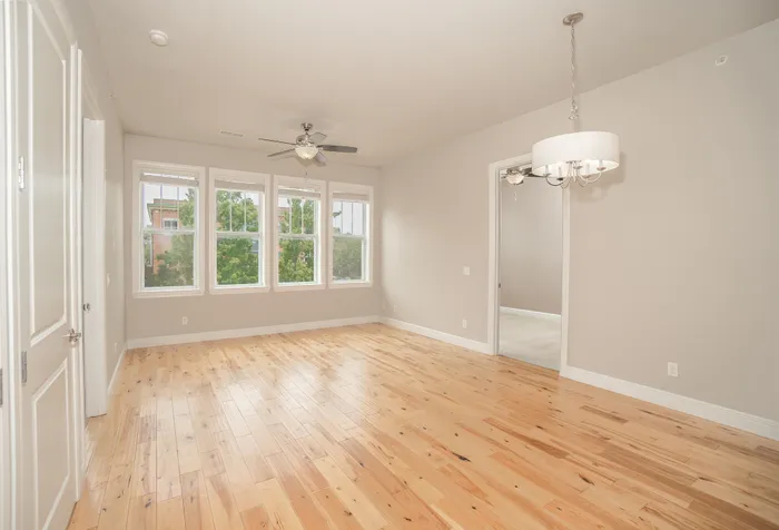 Bright and airy living room with hardwood floors, large windows, and elegant lighting in a modern apartment.