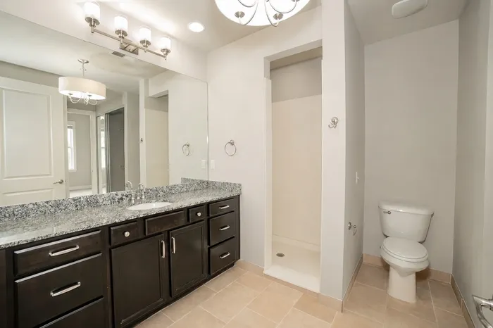 Modern bathroom featuring a sleek granite countertop, elegant cabinetry, and contemporary lighting fixtures.