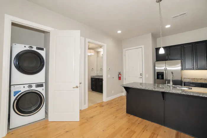 Modern kitchen with sleek granite countertops, stainless steel appliances, and an integrated laundry space for convenience.