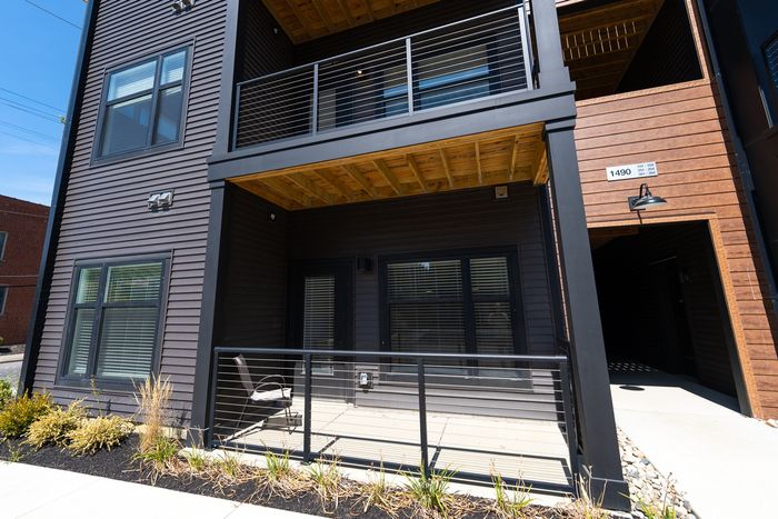 Contemporary apartment complex with vibrant street art, rooftop seating, and lush surroundings.