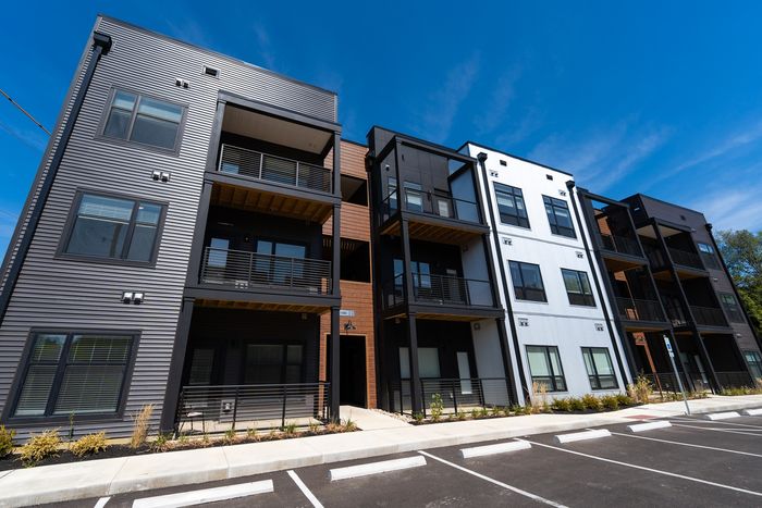 Contemporary apartment complex with vibrant street art, rooftop seating, and lush surroundings.