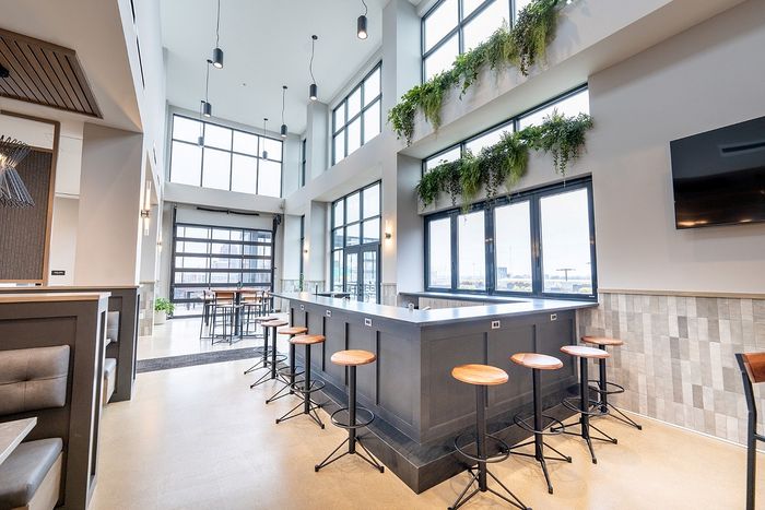 Bright, modern lounge with high ceilings, bar seating, and large windows.