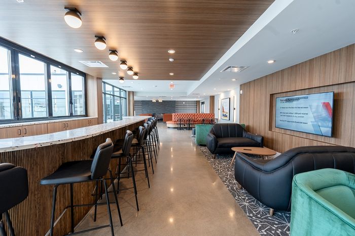 Chic communal lounge with a modern bar area, plush seating, and abundant natural light from large windows.