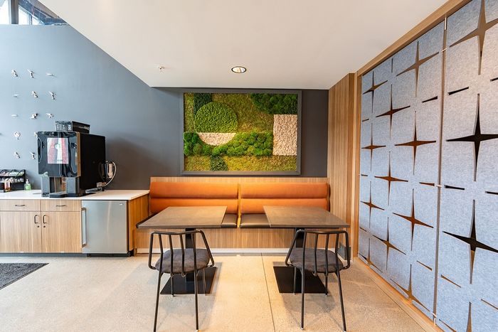 Chic communal area with a modern coffee station, artistic wall decor, and cozy seating in a stylish apartment complex.