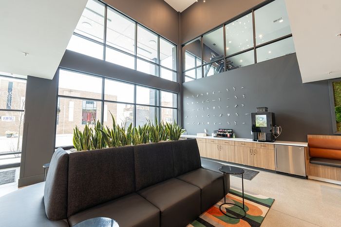 Modern lobby with stylish seating, large windows, and a sleek coffee station offering a welcoming atmosphere.