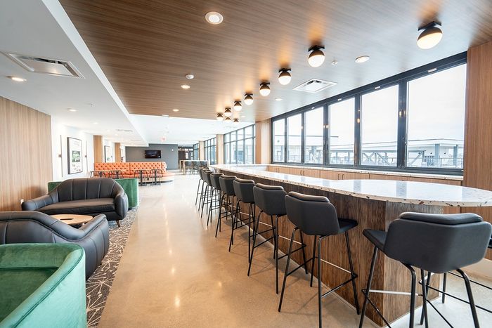 Modern communal area with sleek leather seating, long bar counter, and panoramic windows offering ample natural light.