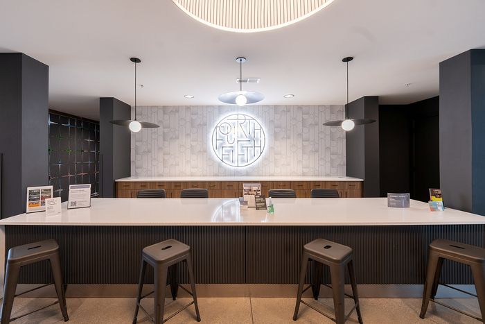 Modern communal space with chic high chairs, stylish pendant lighting, and a sleek countertop, offering a perfect blend of functionality and contemporary design.